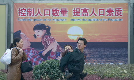 A couple with a small child walk past a propaganda poster promoting the single child policy